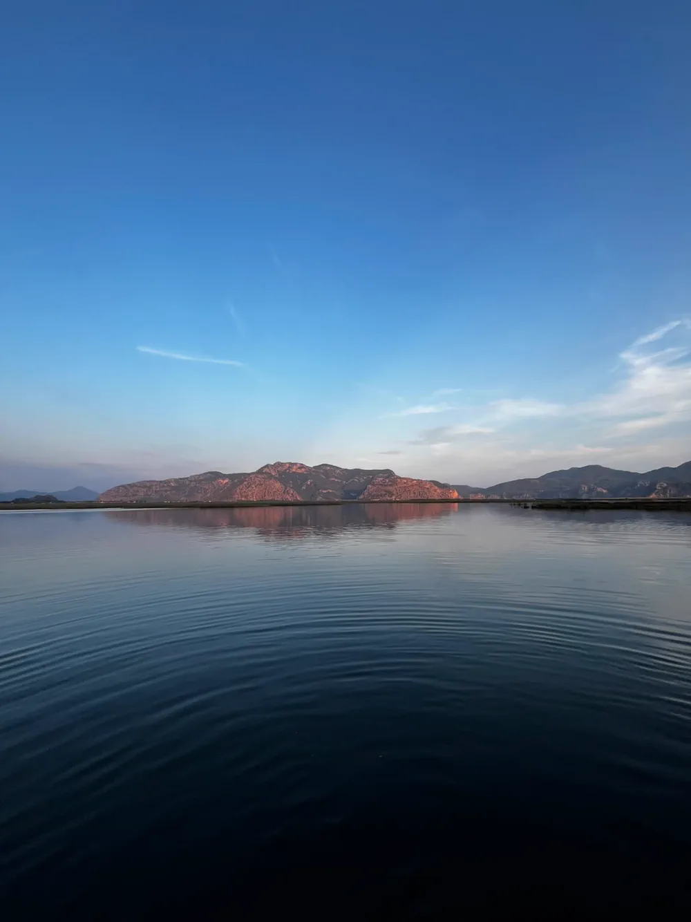 Akşam ışığında Dalyan deltası; pembeye dönmüş dağ sırası ve suya düşen yansıması