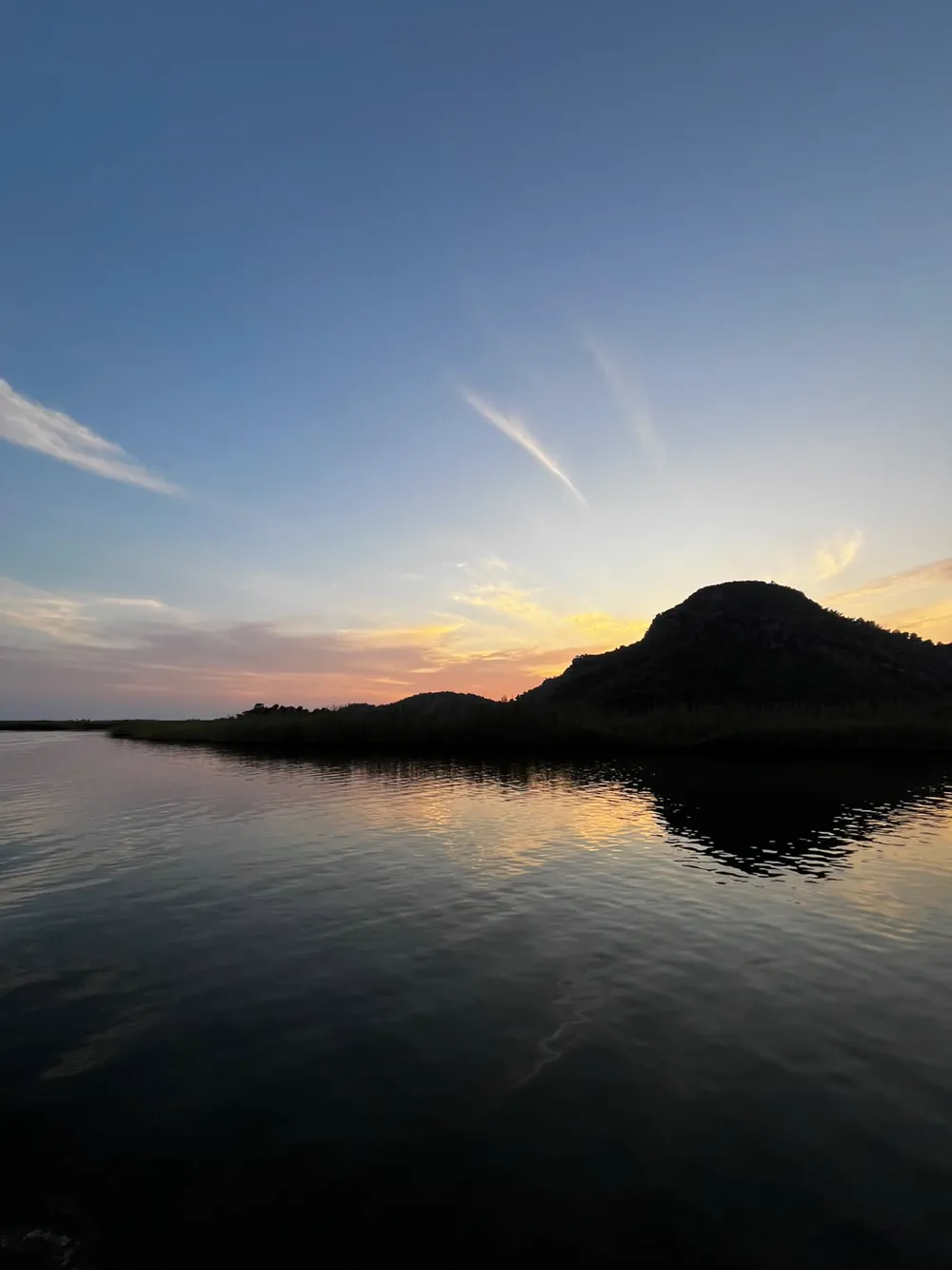 Akşam karanlığı inerken Dalyan Çayı, önde sazlık şeridi ve arkada tepe silueti