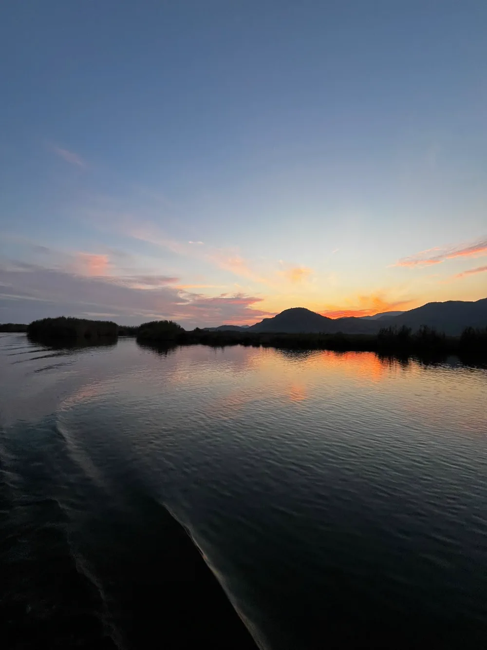 Dalyan Çayı’nda gün batımı; sazlık adacıkları, pembe turuncu bulutlar ve suda uzayan ışık yansıması