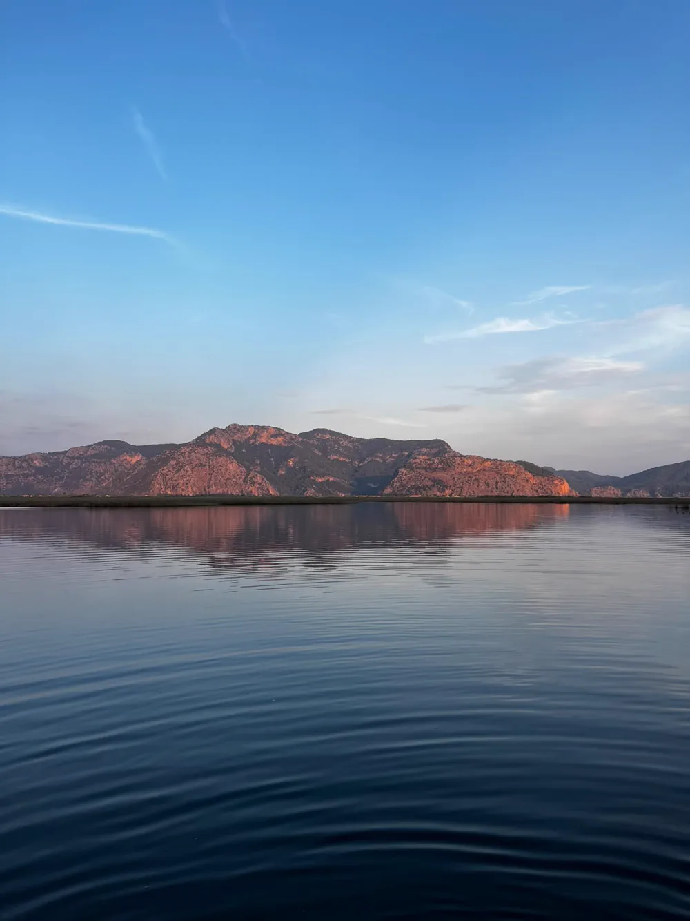 Akşam ışığında pembeye dönen dağ sırası ve Dalyan deltasının durgun suyundaki yansıması