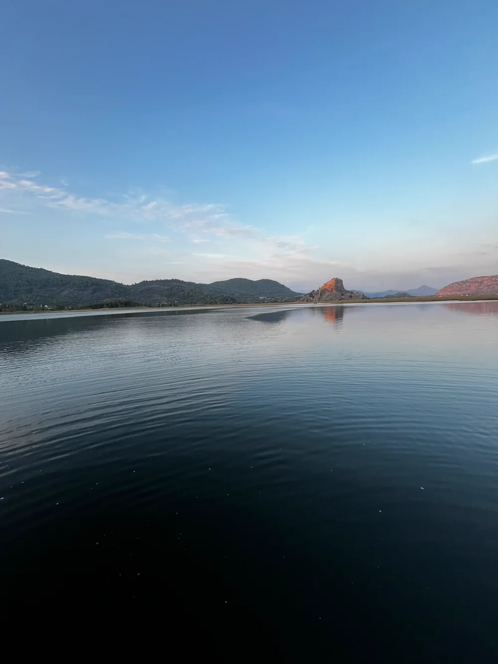 Alacakaranlıkta Dalyan deltası; uzakta son ışığı alan kayalık tepe ve hareketsiz su