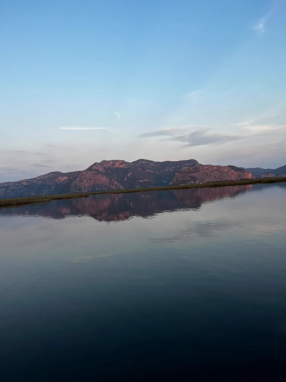 Akşam ışığında Dalyan deltası; karşıdaki dağ sırası pembeye dönmüş, su neredeyse hareketsiz