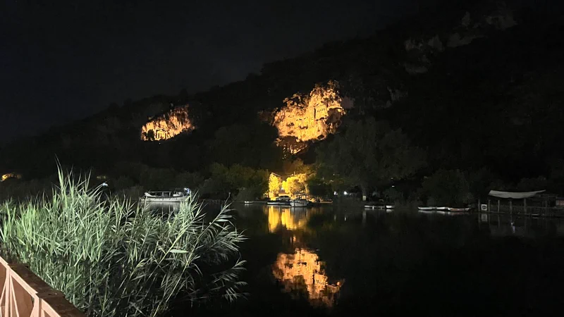 Gece ışıklandırılmış Dalyan kaya mezarları ve nehirdeki turuncu yansıması