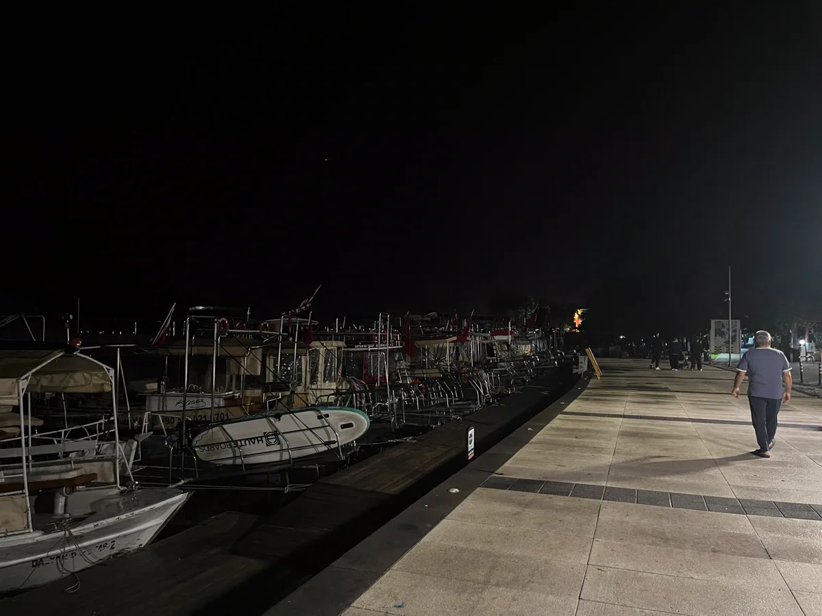 Gece Dalyan iskelesine bağlı tur tekneleri ve kordondaki taş yürüyüş yolu