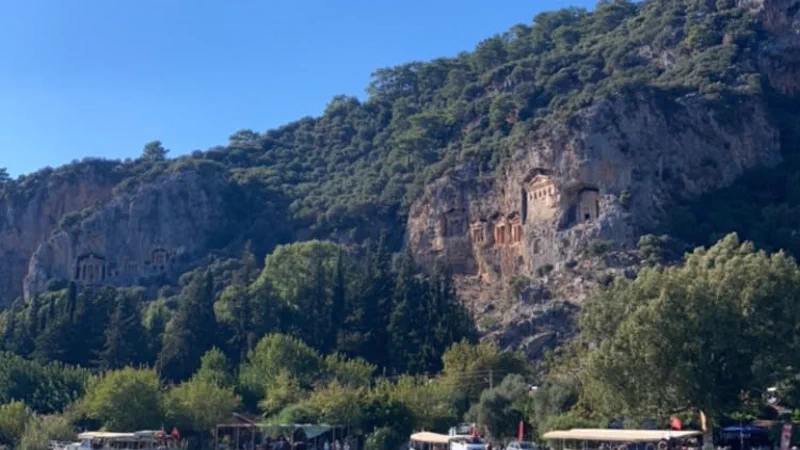 Dalyan kordonundan karşı kayalıktaki Kaunos kral mezarları ve kıyıdaki tur tekneleri