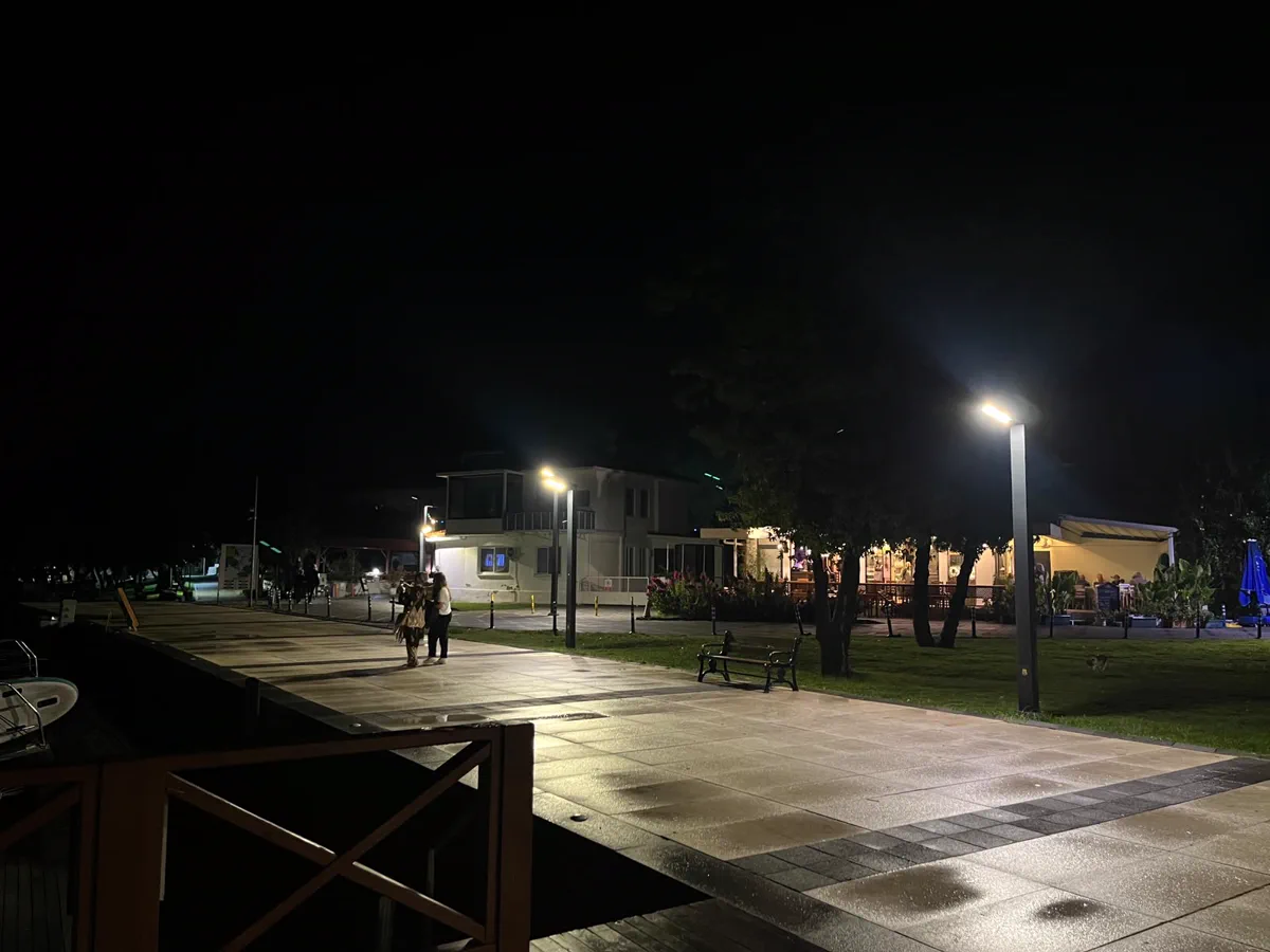 Gece kordon boyunda ışıkları yanan kafe ve restoran terasları, yürüyen insanlar