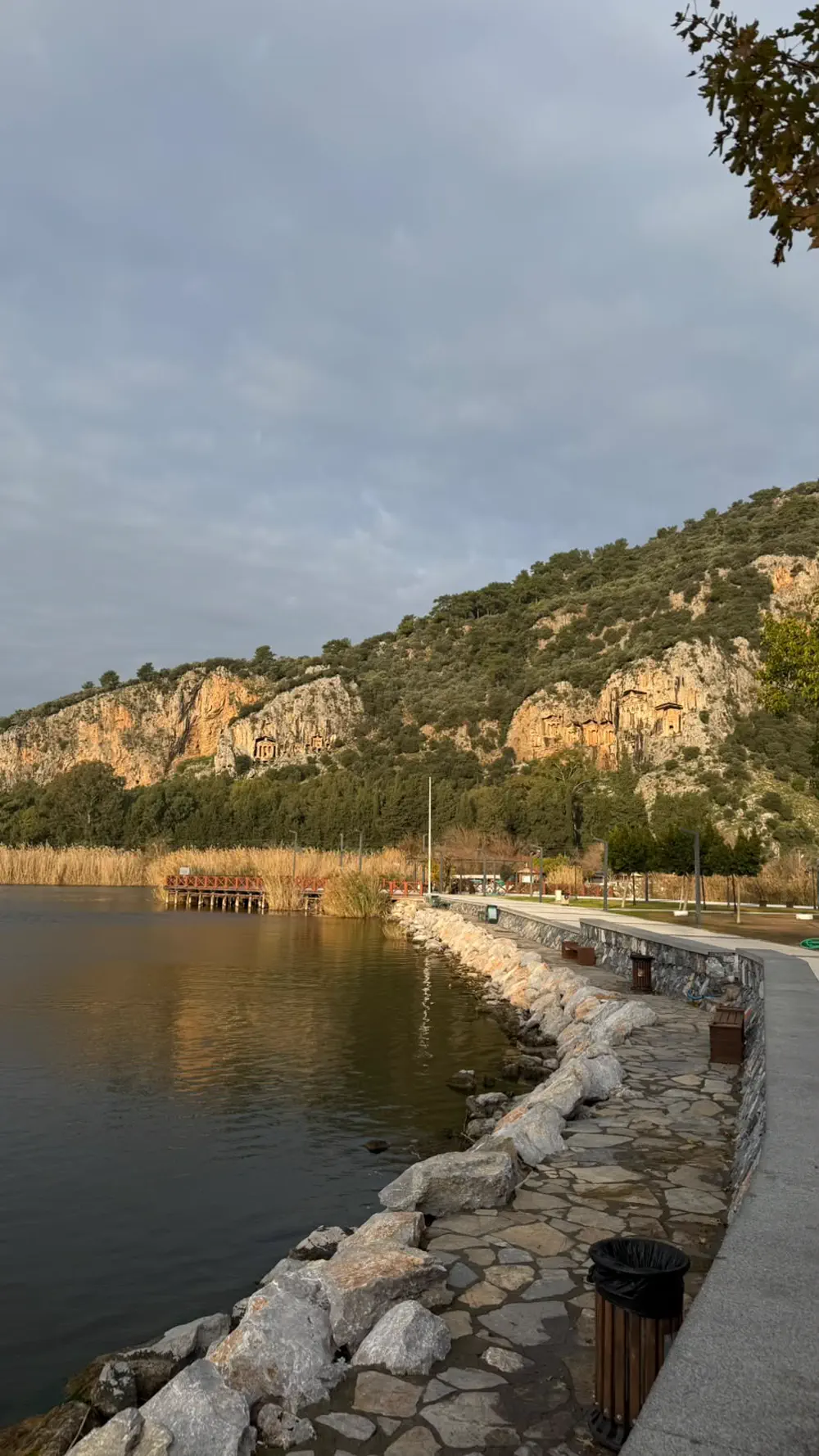 Sezon dışında Dalyan kordonu: taş yürüyüş yolu boş, karşıda kaya mezarları son ışığı alıyor