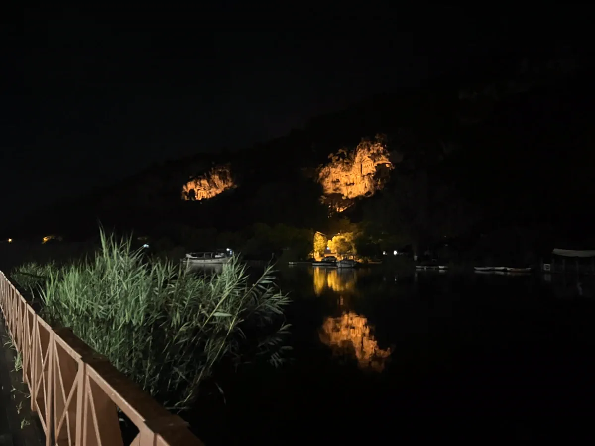 Gece ışıklandırılmış Dalyan kral mezarları, kordonun ahşap korkuluğu ve suya vuran ışık
