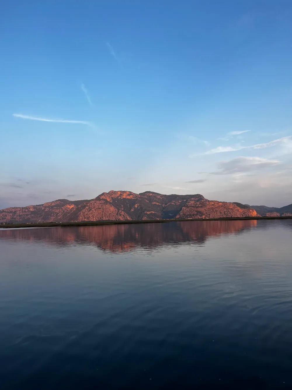 Rüzgârsız bir akşamda ayna gibi duran Dalyan deltası ve suya yansıyan pembe ışıklı dağlar