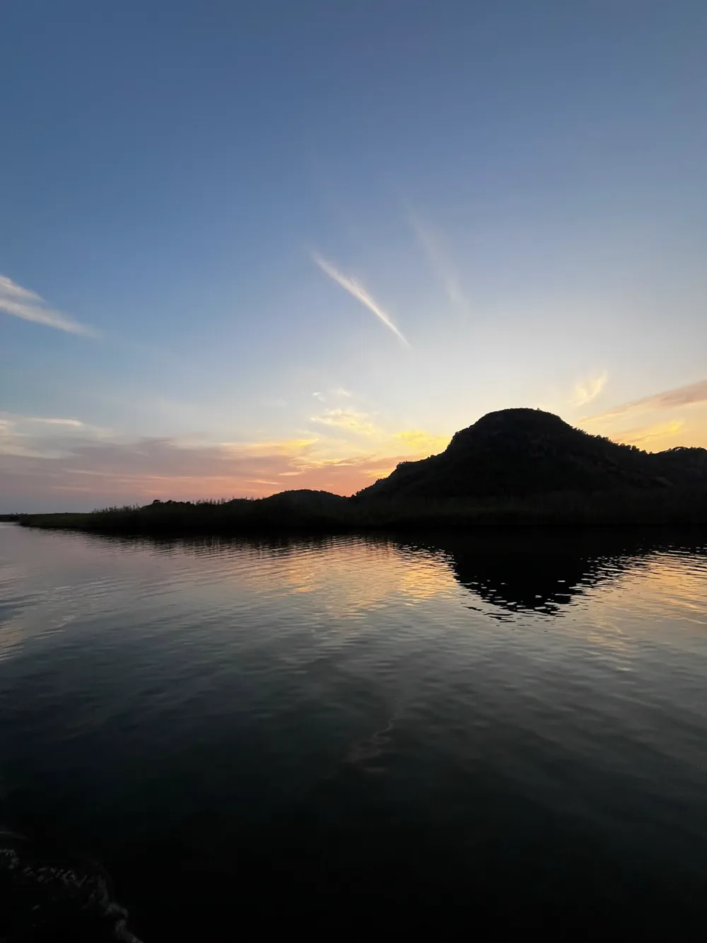 Gün batımında Dalyan Çayı; sazlık şeridi, tepe silueti ve suya vuran sarı ışık