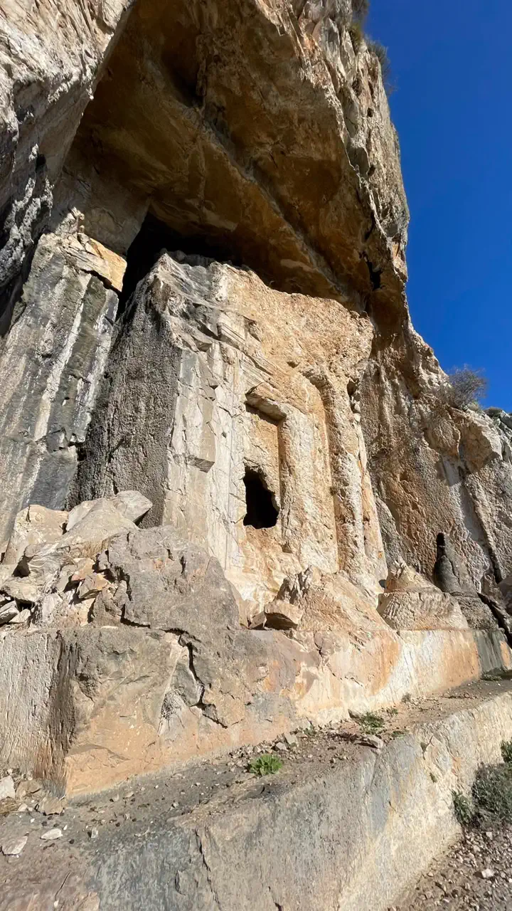 Kaunos nekropolünde kayaya oyulmuş mezar cephesi; sütunları ve kapı boşluğu kabaca bırakılmış